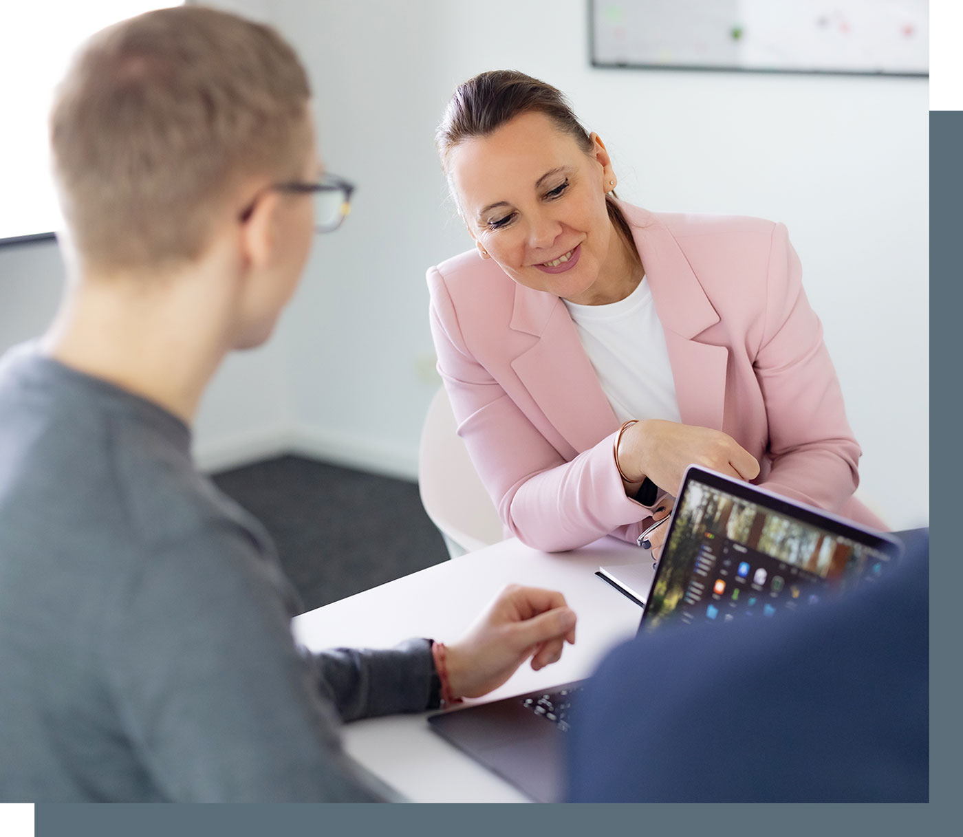 Besprechung in der Steuerberaterkanzlei, Steuerberaterin Ina Bergen schaut auf den Laptop eines Kollegen und lächelt