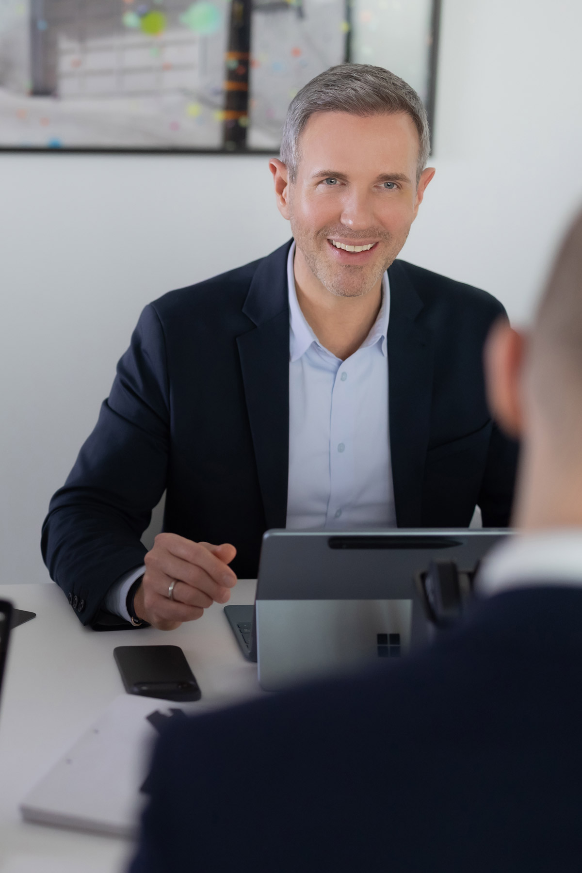 Benjamin Vogel, Steuerberater und Partner bei RV, sitzt am Besprechungstisch und hat einen Laptop vor sich stehen