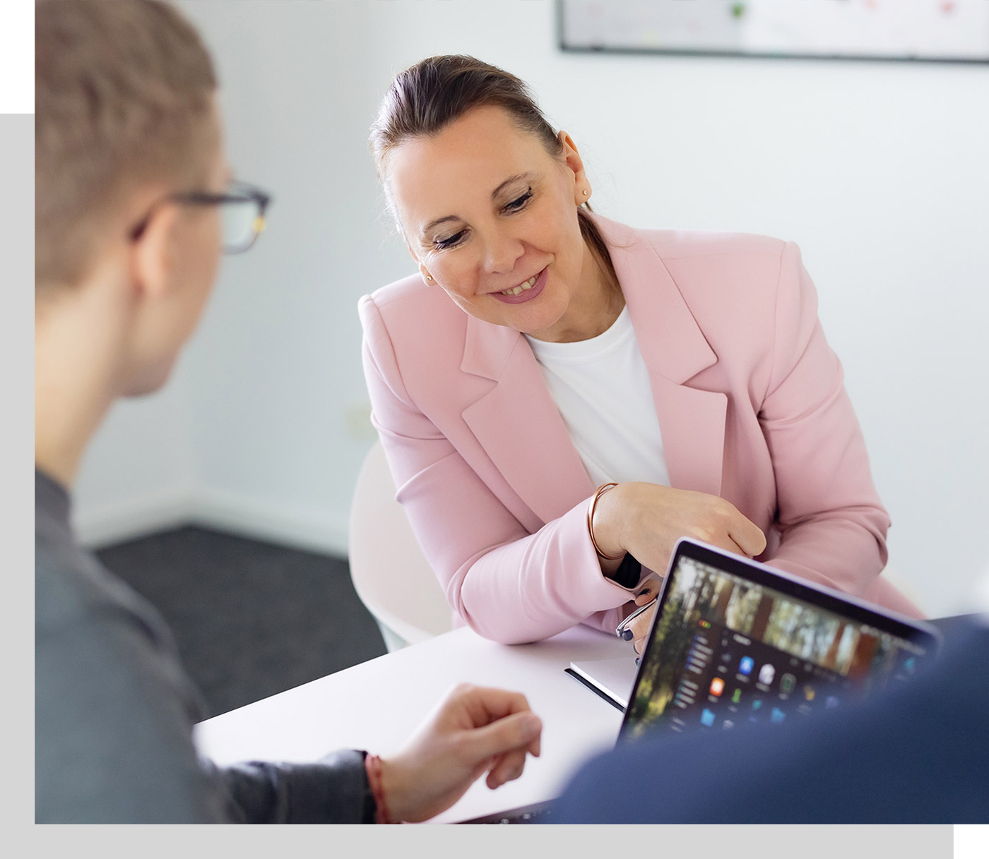 Besprechung in der Steuerberaterkanzlei, Steuerberaterin Ina Bergen schaut auf den Laptop eines Kollegen und lächelt