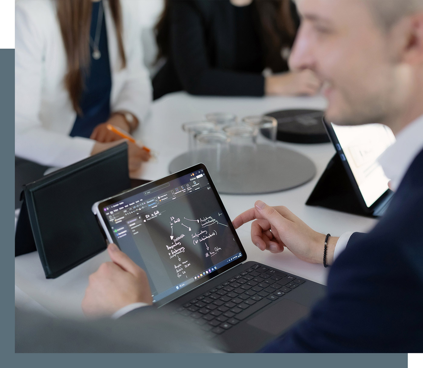 Detailansicht eines Tablets während einer Besprechung, auf dem Tablet sind schematisch Strukturen und Abläufe skizziert