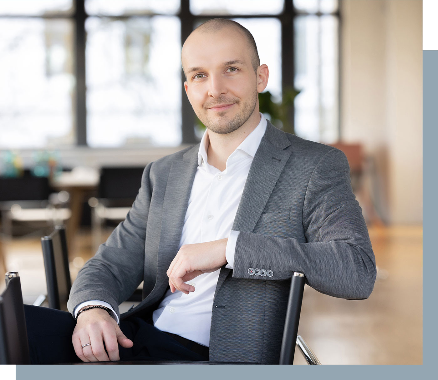 Portrait von Steuerberater Alexander Schmackey, er sitzt entspannt und lächelnd auf einem Stuhl