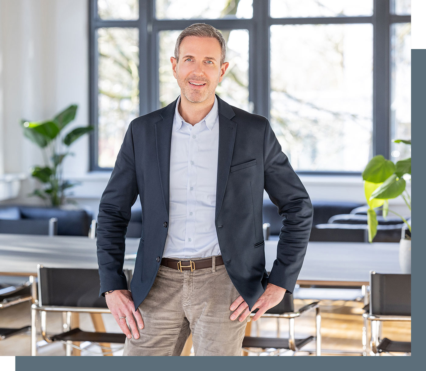 Steuerberater Benjamin Vogel steht in einem hellen Besprechungsraum und schaut freundlich in die Kamera