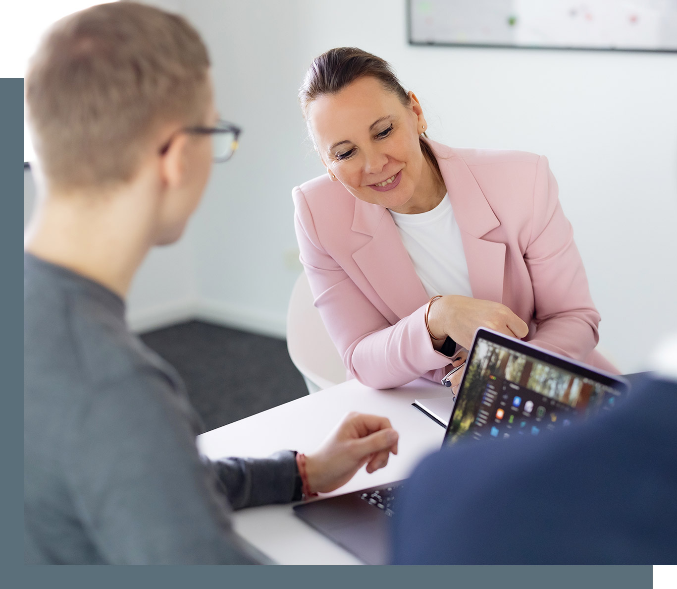 Besprechung in der Steuerberaterkanzlei, Steuerberaterin Ina Bergen schaut auf den Laptop eines Kollegen und lächelt