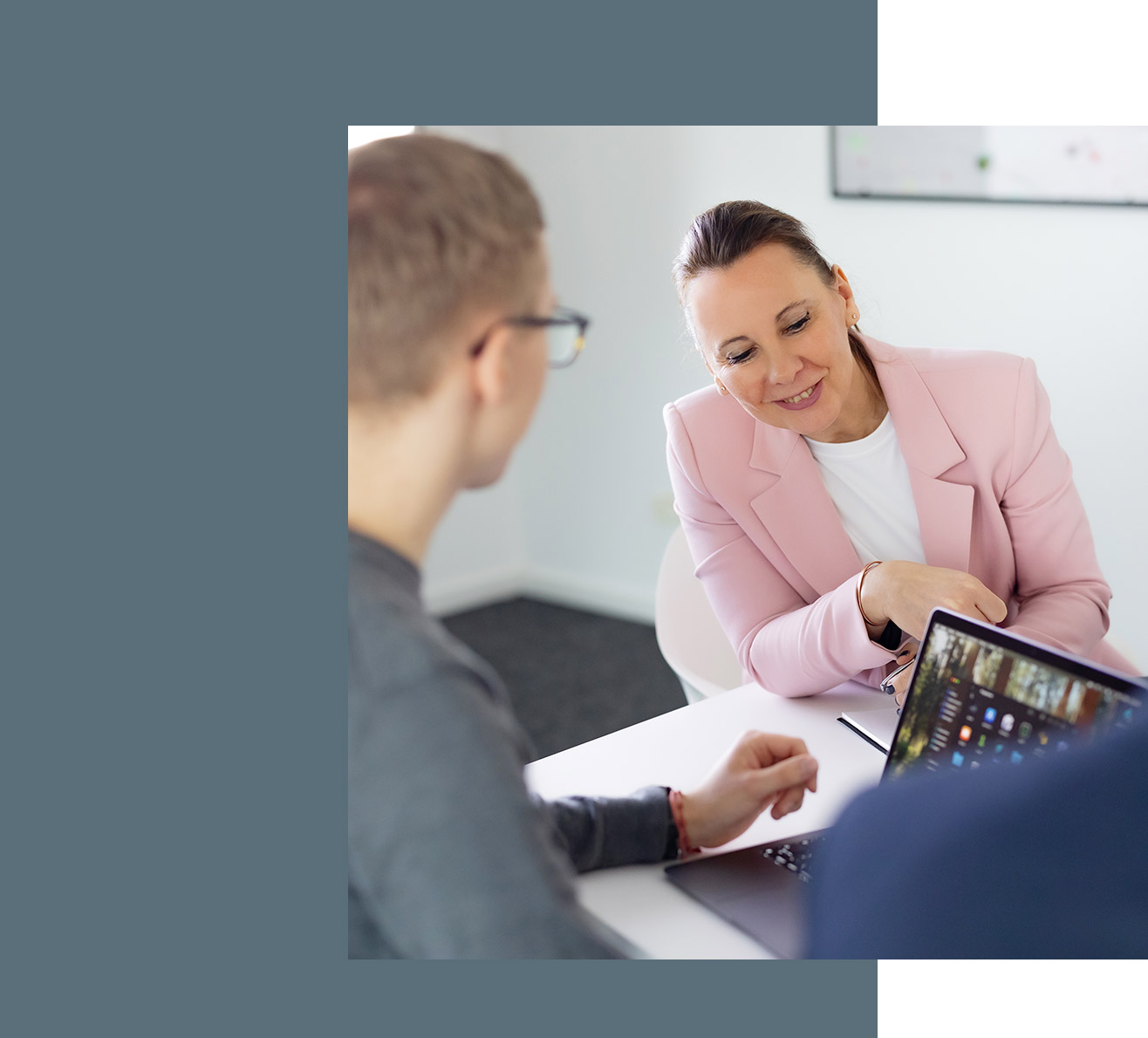 Besprechung in der Steuerberaterkanzlei, Steuerberaterin Ina Bergen schaut auf den Laptop eines Kollegen und lächelt