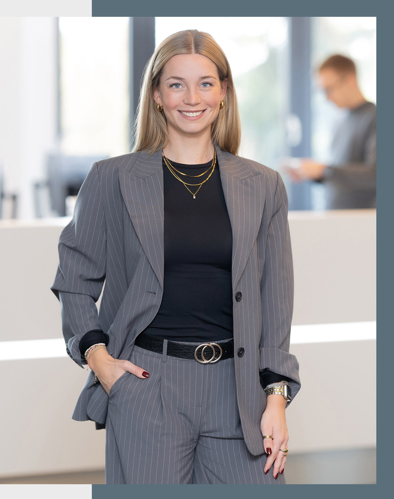 Kanzleimanagerin Henriette steht lächelnd vor dem Empfang der Kanzlei