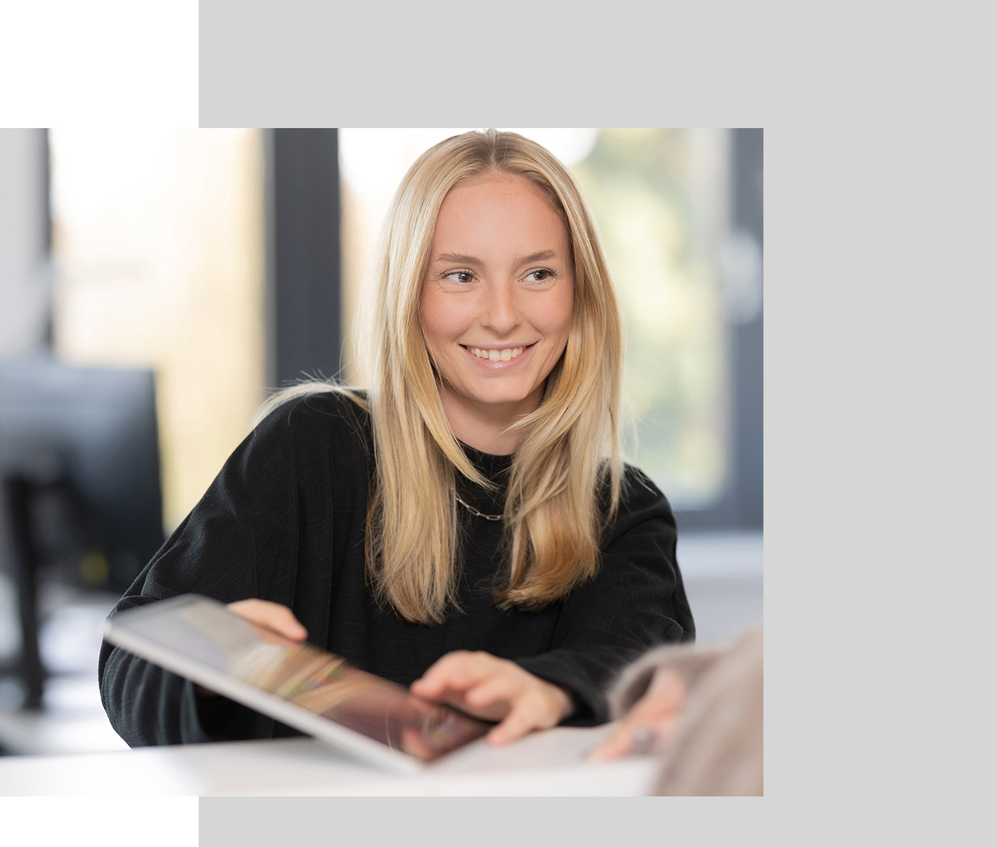 Eine Mitarbeiterin am Empfang zeigt einer Mandantin Unterlagen auf dem Tablet